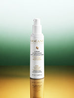 Flacon de Crème Hydratante Anti-imperfections ODÉANE, 50 ml, sur une surface réfléchissante et un fond dégradé vert et doré.
