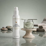 Crème Hydratante Anti-imperfections ODÉANE, 50 ml, près d'un pot de crème blanche et d'une spatule, avec galets et serviettes sur fond vert pâle.