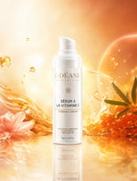Sérum à la vitamine C ODÉANE, 30 ml, près de baies orange et d'une fleur rose sur fond doré avec éclaboussures.