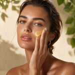 Femme appliquant une texture jaune translucide sur sa joue du bout des doigts.